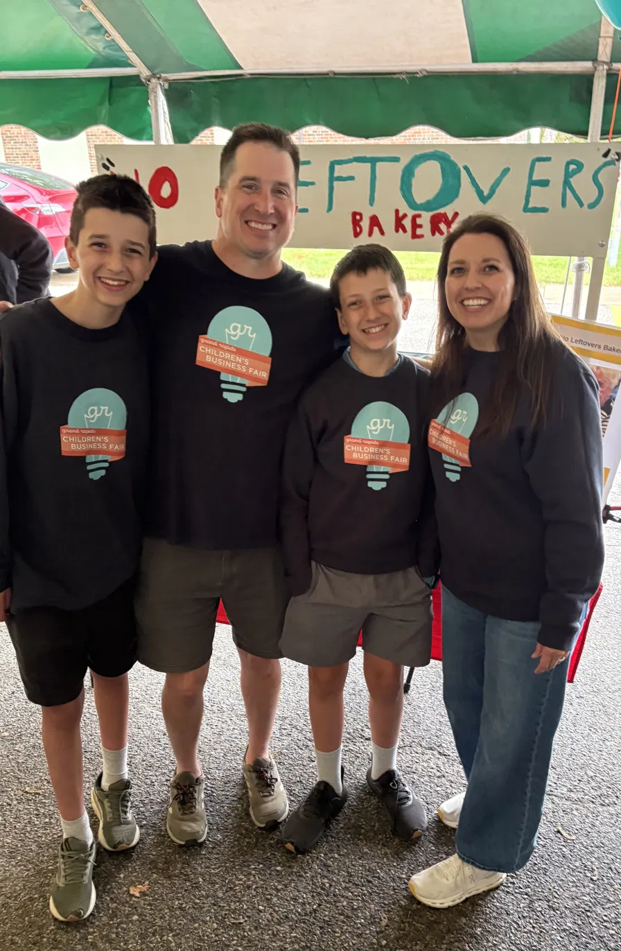 Dana, Matt, and their two sons in matching sweatshirts at the Children's Business Fair